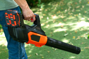 switching season tips. Cordless Leaf Blowers. handheld, cordless, electric leaf blower in a garden, selective focus. Autumn, fall gardening works in a backyard, on a lawn, grass. Garden works.